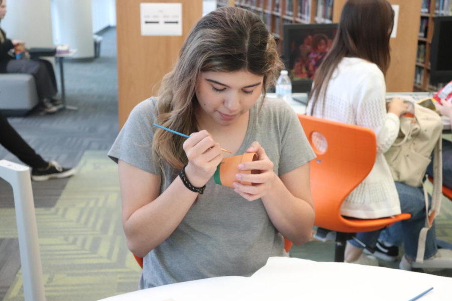 A student paints a flower pot in the library, which was one of the activities in October. 