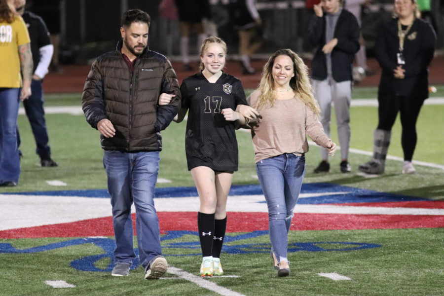 Walking down the field with her family, senior Kyla Giddiens enjoys the special night. 