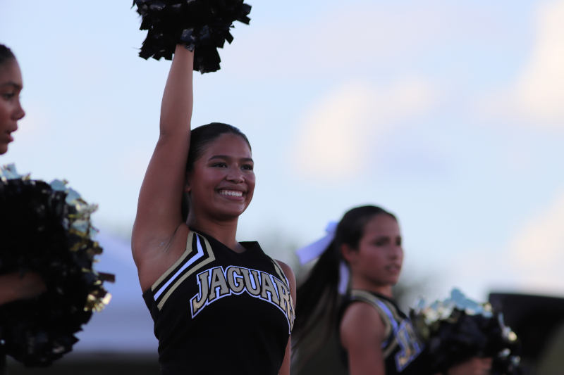 JV cheerleader Karlee Logan smiling on the sidelines.