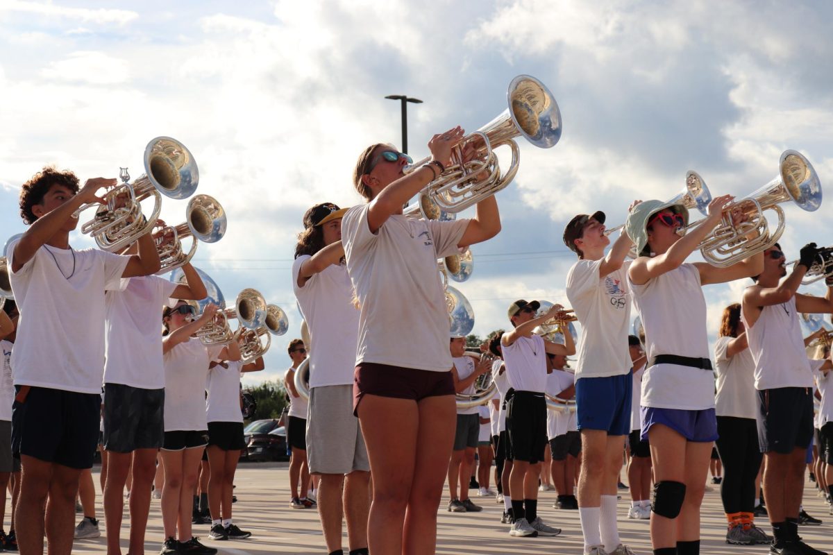 Tuba players Armani Moreno (left), Madeline Wilson (middle), and Josie Blair (right) practicing for the Cedar Ridge football game in the staff parking lot after school.