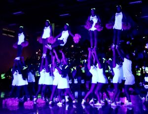 The cheer team performing their stunt under the black lights. 