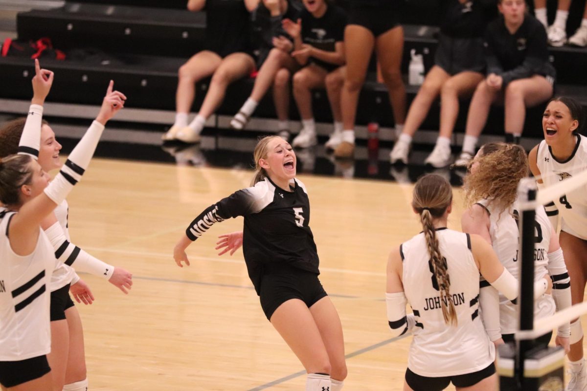 Junior Rileigh Butler joins team in joy over scoring the first point in the fourth set.