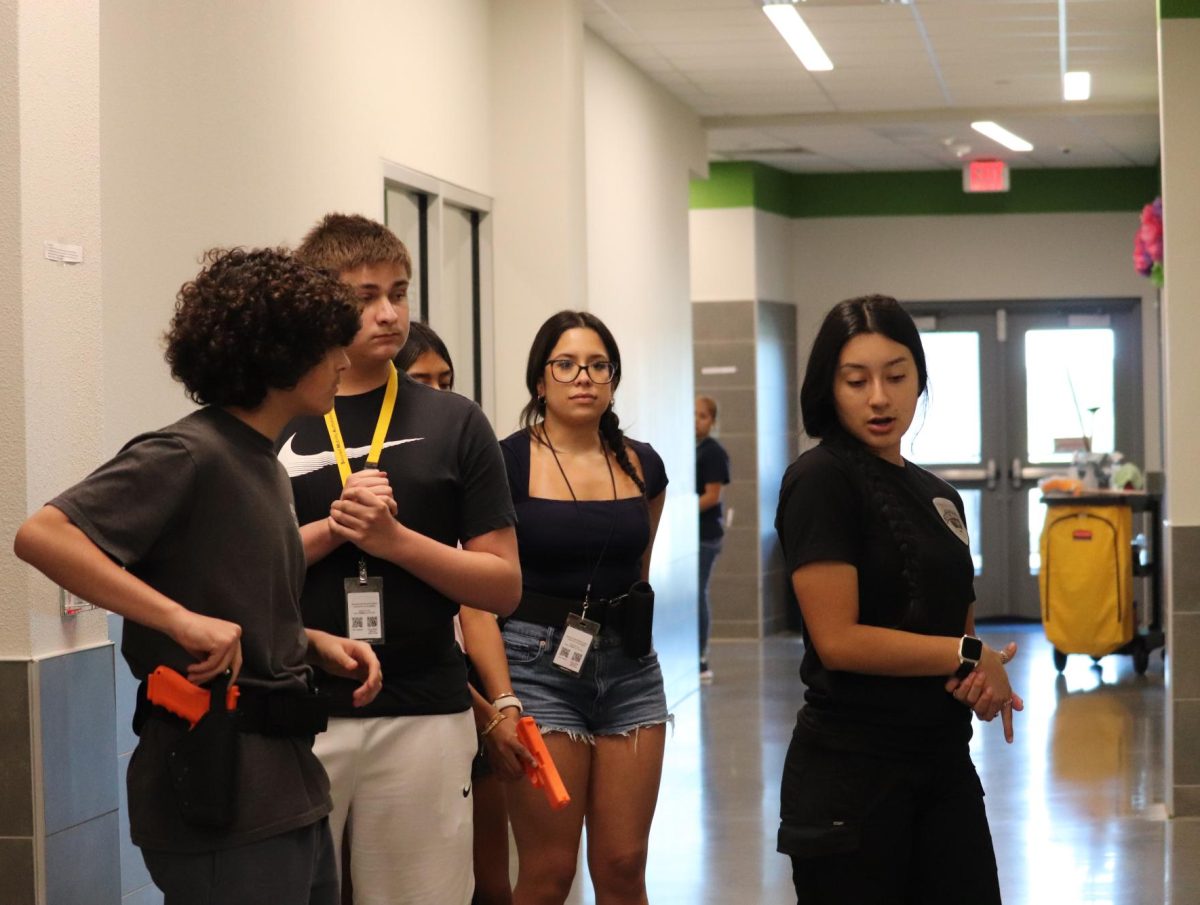 Senior president Kallina Rodriguez instructing new members on firearm safety during a building search.