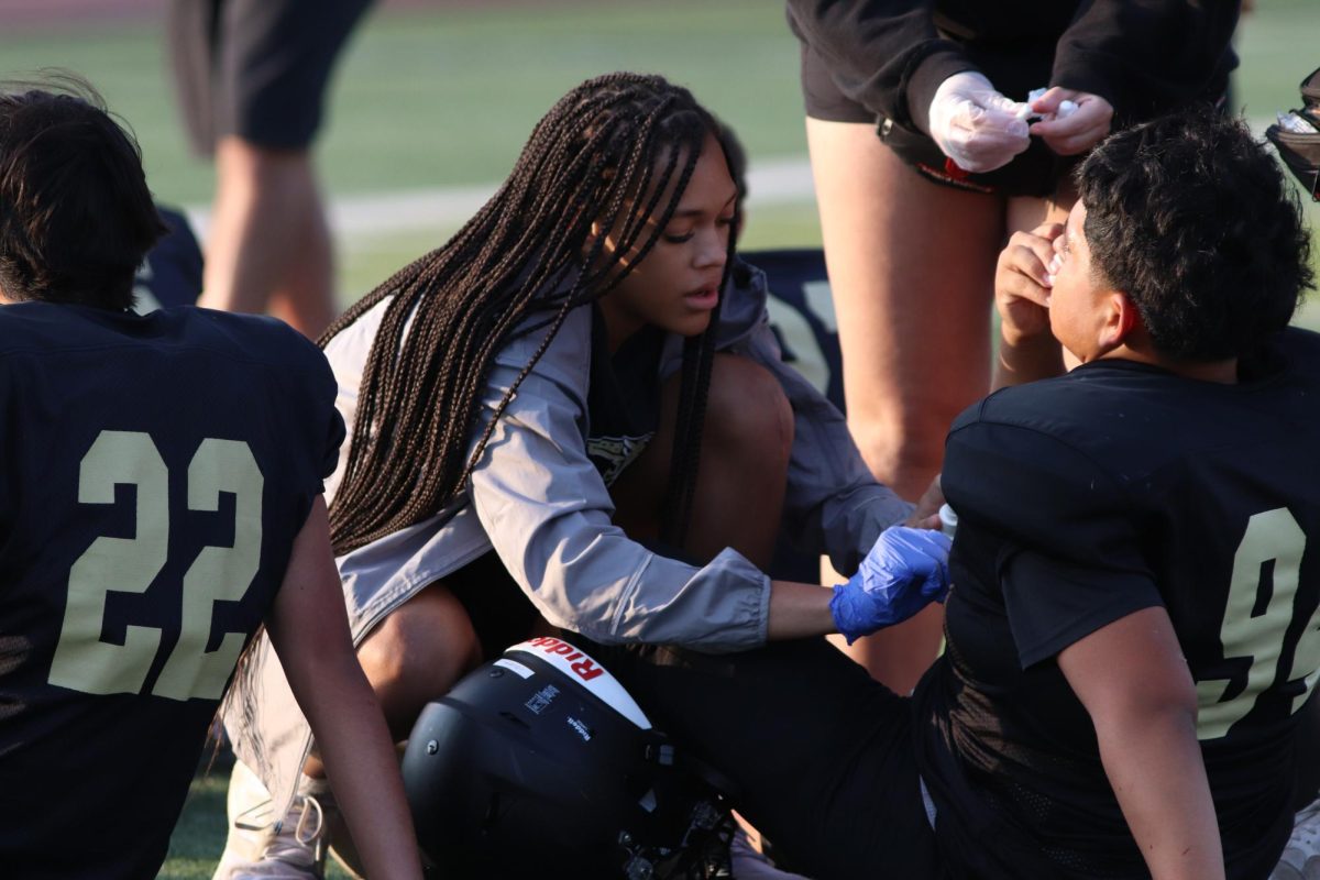 Senior student trainer Zaniah Hoskins helping a JV football player with a nosebleed on Oct. 16. 