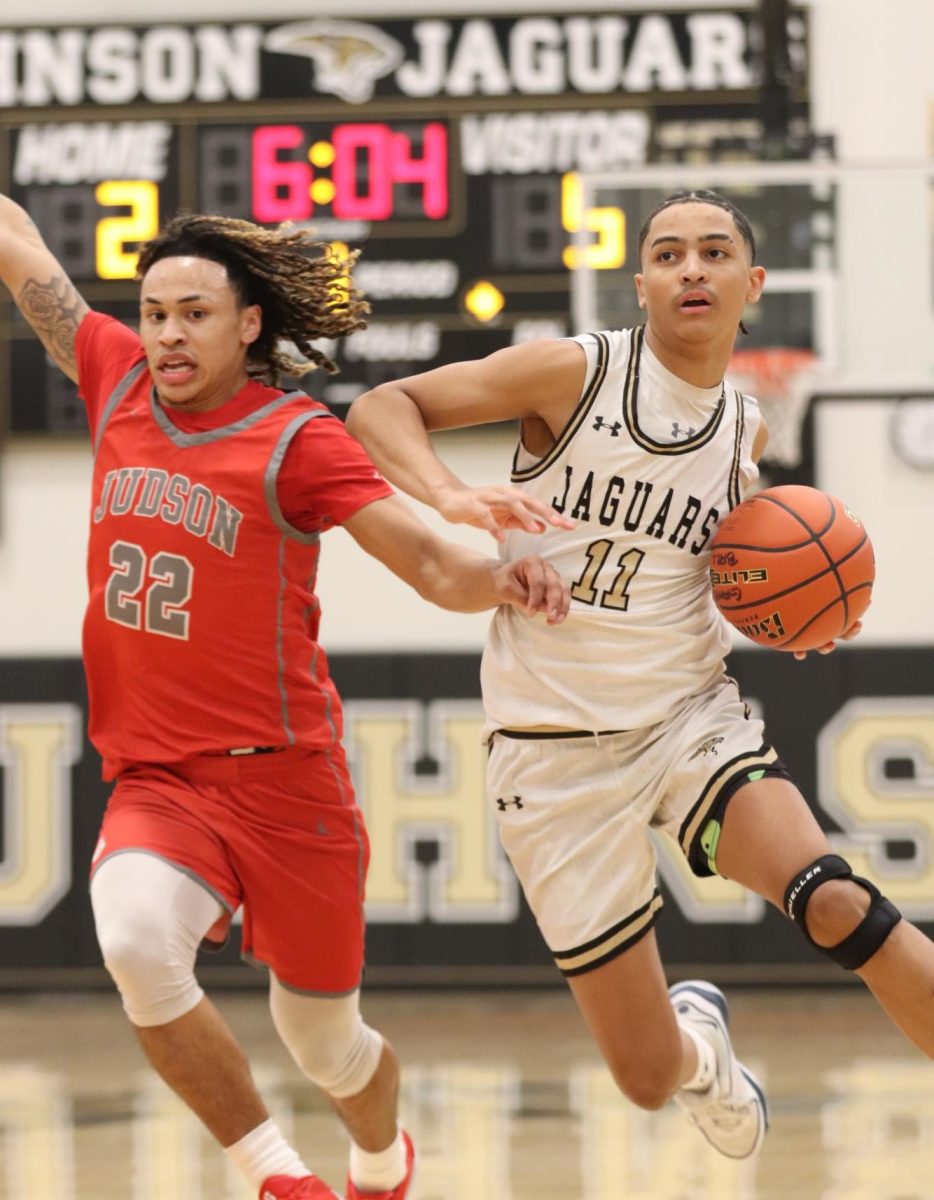 Sophomore Mack Martin running while dribbling the ball and trying to block away his opponent. 