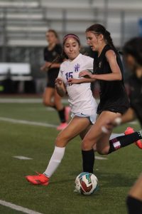 Girls Soccer Captain Jadyn Jaeger dribbling the ball towards the goal net. 