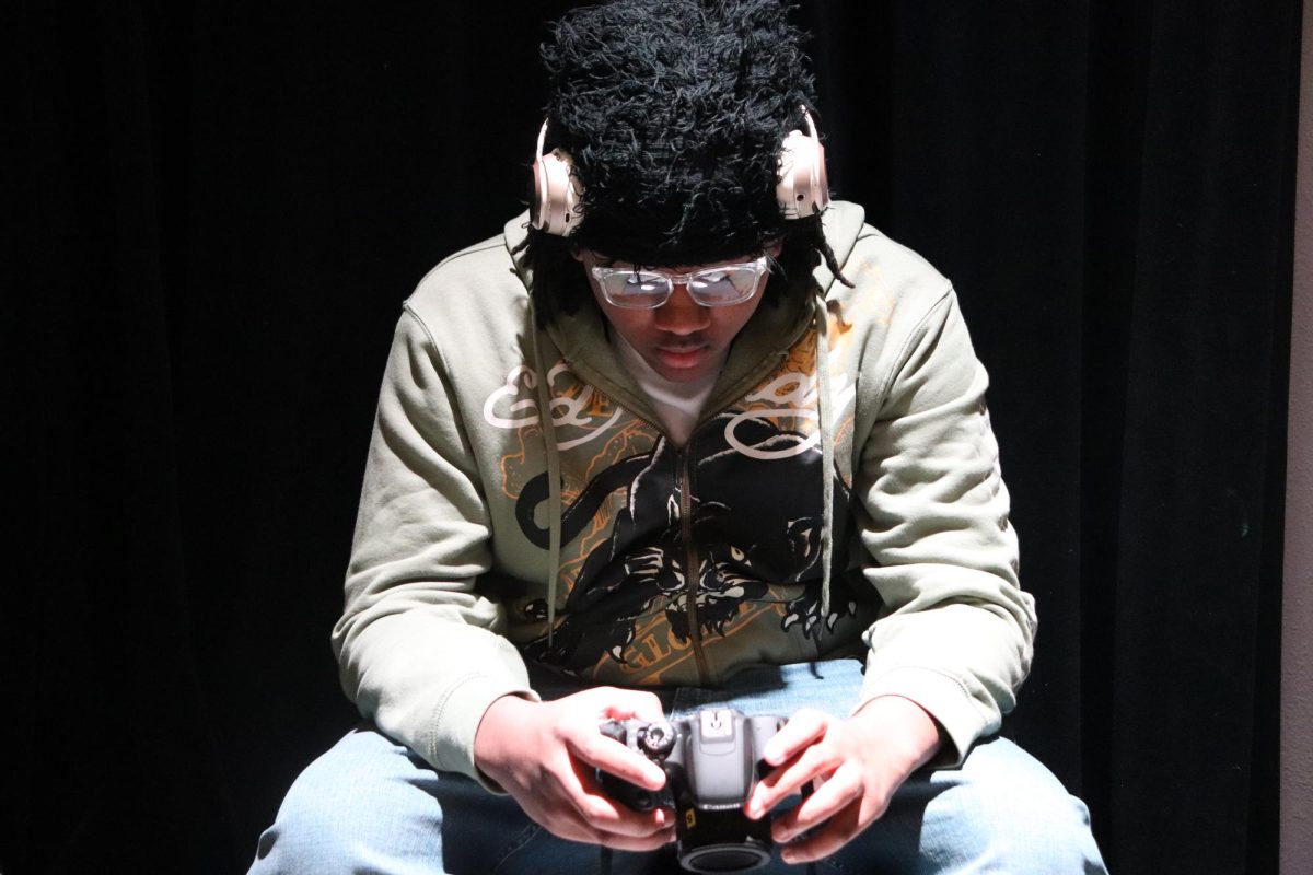 Junior Josiah Woods fumbling with his camera in the AV production studio. 