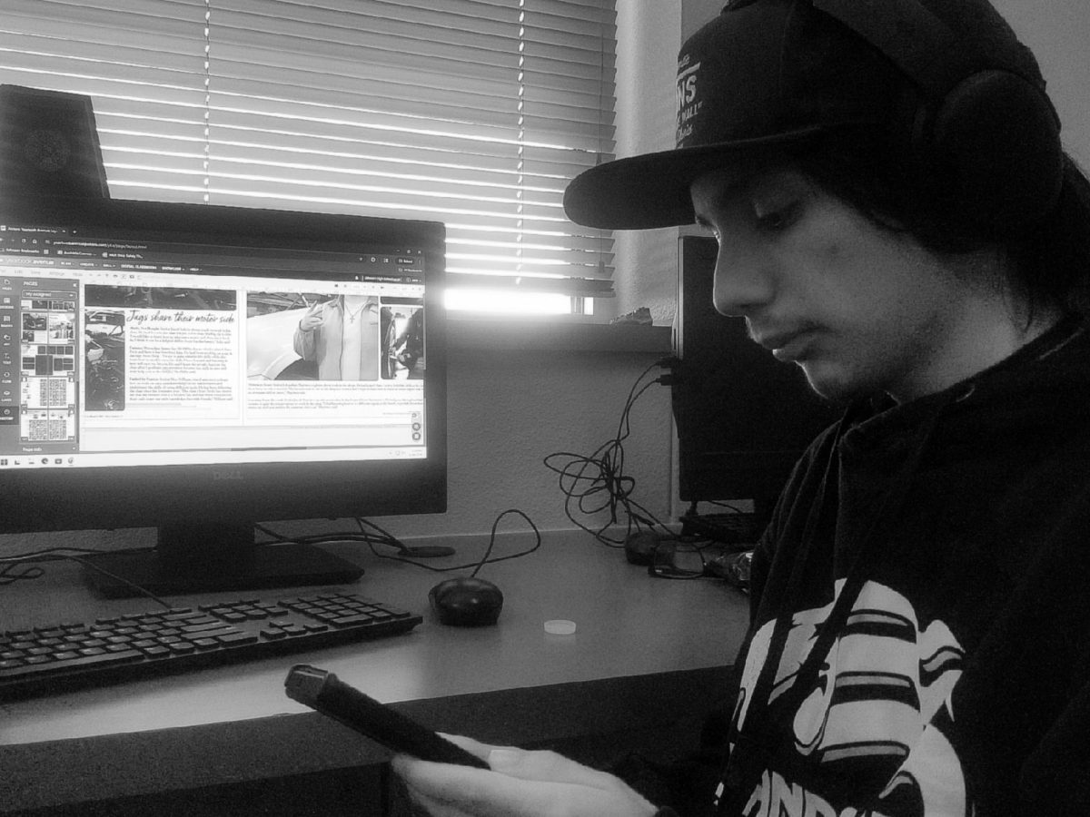 Senior Jette Silva doing yearbook work on his phone.